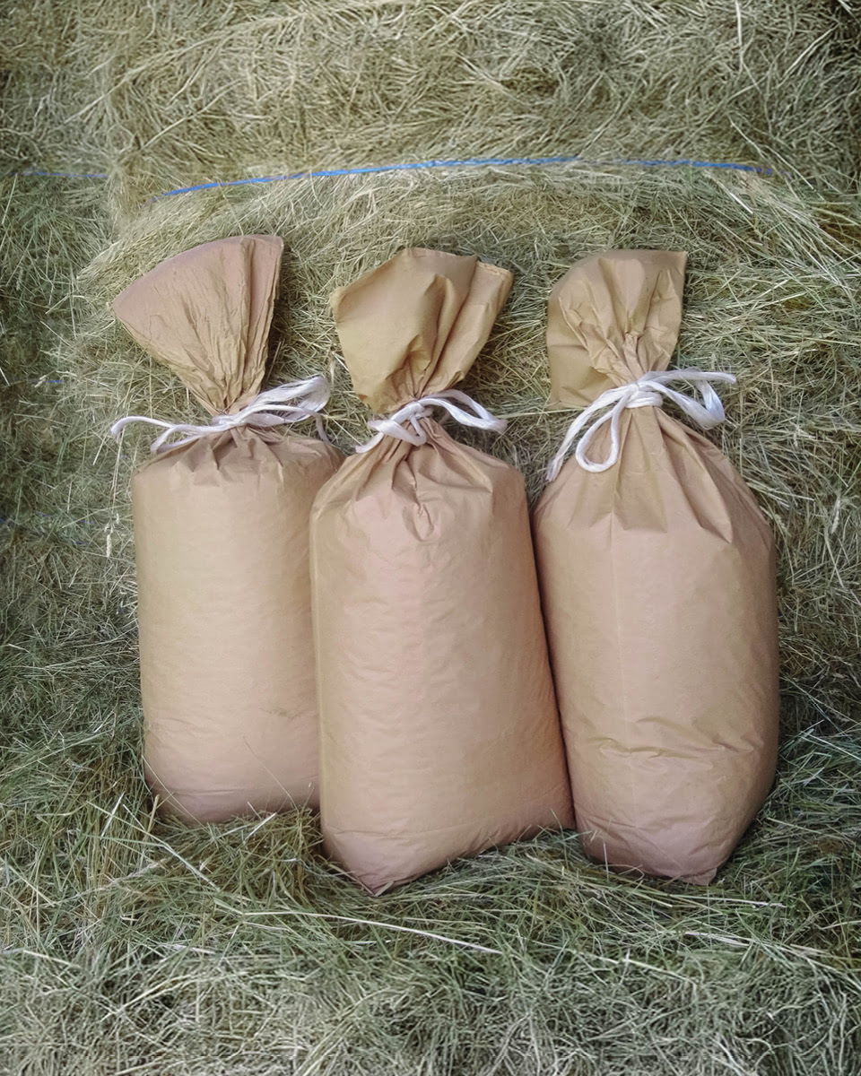 Drei Papiersäcke umgeben von Heu.